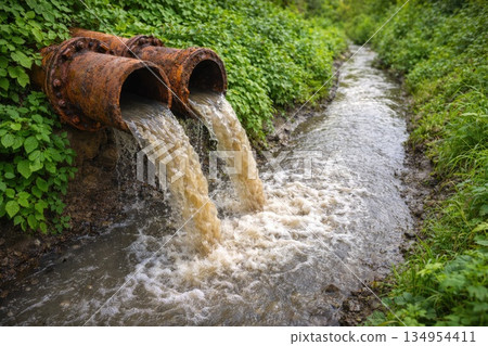 Polluted Wastewater Flowing from Rusty Pipes into Natural Stream Environmental Concept 134954411
