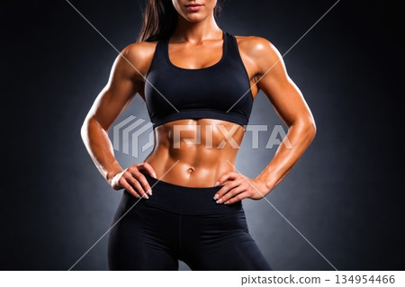 Fit Muscular Woman with Defined Abs Standing Confidently in Black Sportswear Fit Muscular Woman with Defined Abs Standing Confidently in Black Sportswear 134954466