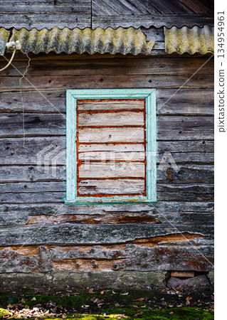 Boarded window of abandoned wooden house with moss growing on wall 134954961