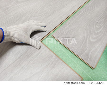 A person is laying down a piece of wood laminate 134956656