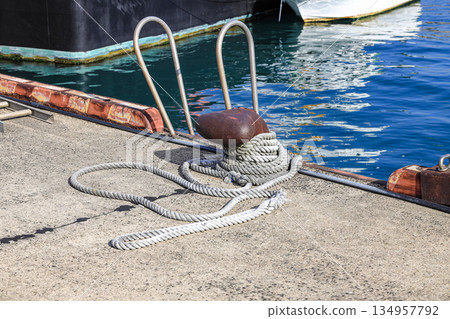 Mooring line on rusty pier bollard referred to a post on a ship or quay. Mooring line on rusty pier bollard referred to a post on a ship or quay. 134957792