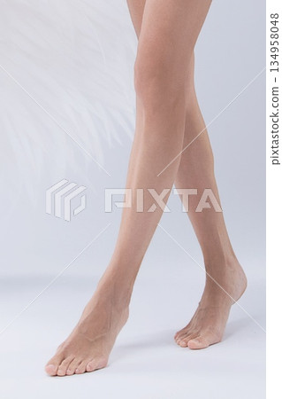 Graceful female legs and bare feet standing on a white studio background 134958048