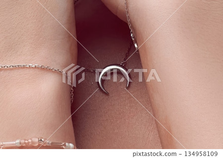 Close-up of a woman wearing a silver crescent moon necklace and bracelets Close-up of a woman wearing a silver crescent moon necklace and bracelets 134958109