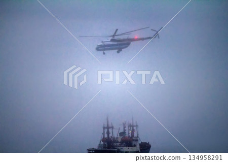 Helicopter performs loading operations on icebreake in fog Helicopter performs loading operations on icebreake in fog 134958291