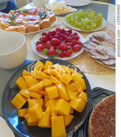 A table with a variety of food including a black bowl of mangoes 134958460