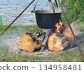 A large pot is on a tripod over a fire 134958481