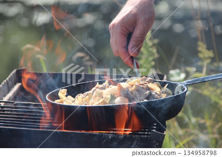Cooking fried mussels in frying pan. Frying fresh mussels and onions near river Cooking fried mussels in frying pan. Frying fresh mussels and onions near river 134958798