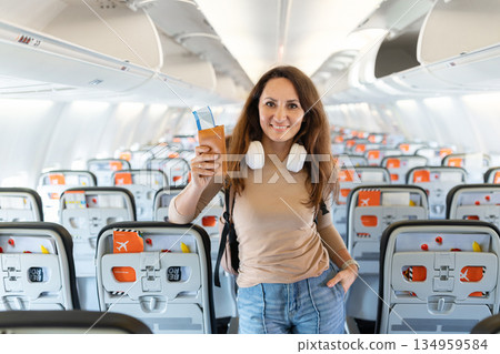 Portrait of happy adult caucasian woman holding passport inside airplane cabin Portrait of happy adult caucasian woman holding passport inside airplane cabin 134959584