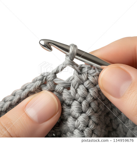 Close-up of a person's hands crocheting with a light grey yarn and a metal hook, showcasing the craft process for diy and hobby content Close-up of a person's hands crocheting with a light grey yarn and a metal hook, showcasing the craft process for diy and hobby content 134959676