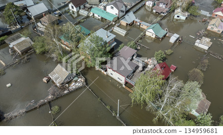 Aerial drone footage of a massive city flood with houses and streets submerged under water. Urban flooding caused by extreme weather and heavy rainfall, showing natural disaster impact on residential  134959681