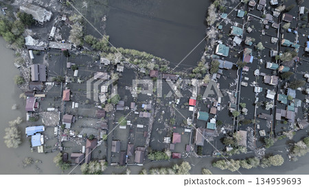 Aerial drone footage of a massive city flood with houses and streets submerged under water. Urban flooding caused by extreme weather and heavy rainfall, showing natural disaster impact on residential  134959693