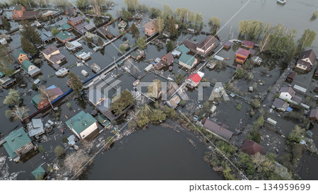 Aerial drone footage of a massive city flood with houses and streets submerged under water. Urban flooding caused by extreme weather and heavy rainfall, showing natural disaster impact on residential  134959699