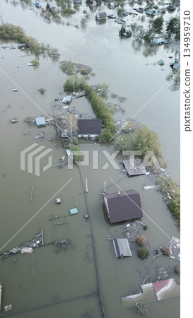 Aerial drone footage of a massive city flood with houses and streets submerged under water. Urban flooding caused by extreme weather and heavy rainfall, showing natural disaster impact on residential  134959710