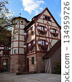 Charming Half-Timbered House With Flower Boxes In Cobblestone Courtyard, European Village Charm 134959726