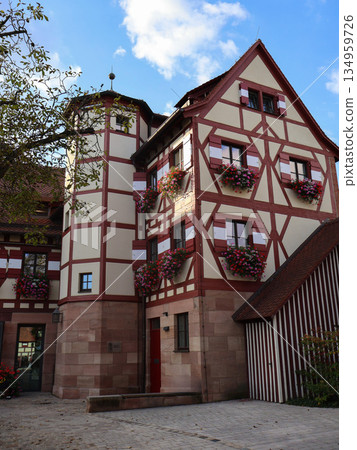 Charming Half-Timbered House With Flower Boxes In Cobblestone Courtyard, European Village Charm Charming Half-Timbered House With Flower Boxes In Cobblestone Courtyard, European Village Charm 134959726