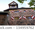 Charming European Stone Building With Red And White Diagonal Shutters And Timber Tower 134959762
