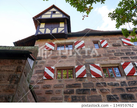 Charming European Stone Building With Red And White Diagonal Shutters And Timber Tower Charming European Stone Building With Red And White Diagonal Shutters And Timber Tower 134959762