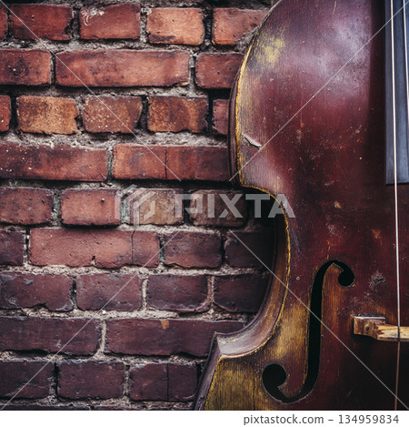 photo with the image of a contrabass against the background of an old brick wall, falling sunlight 134959834