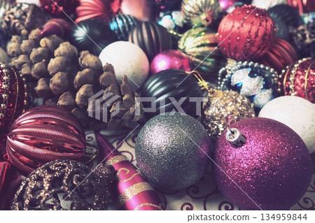 Colorful decorations fill the scene, capturing the joy of Christmas and New Year celebrations. Shiny ornaments and pinecones create a lively and cozy atmosphere, inviting warmth and cheer Colorful decorations fill the scene, capturing the joy of Christmas and New Year celebrations. Shiny ornaments and pinecones create a lively and cozy atmosphere, inviting warmth and cheer 134959844