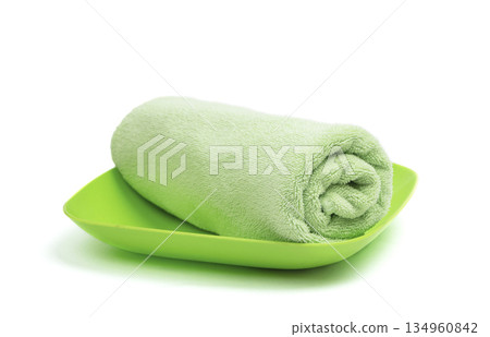 Green folded towel  arranged on a light surface, offering a clean space for branding and text placement. 134960842