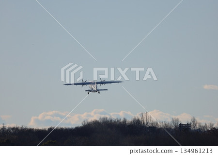 A small propeller passenger plane takes off into the blue sky 134961213