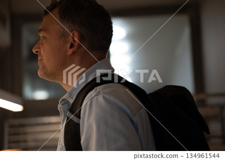 Man standing in bakery with backpack and thoughtful look Man standing in bakery with backpack and thoughtful look 134961544