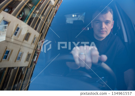 Man behind the wheel seen through windshield Man behind the wheel seen through windshield 134961557