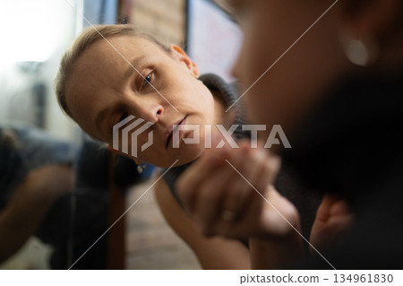 Woman observing her reflection closely in mirror Woman observing her reflection closely in mirror 134961830