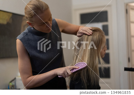 Woman Brushing Another Woman's Hair Indoors 134961835