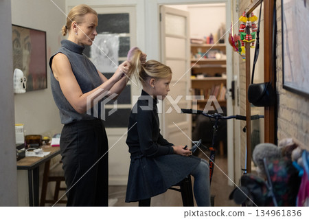 Mother brushing daughter's hair indoors 134961836