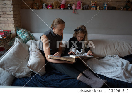 Mother and daughter reading together at home Mother and daughter reading together at home 134961843