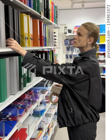 Woman selecting file folders on store shelf 134961872
