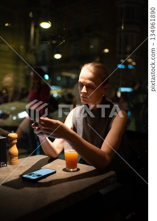 Woman browsing smartphone in dimly lit cafe Woman browsing smartphone in dimly lit cafe 134961890