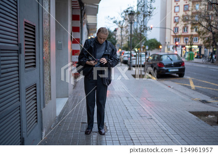 Woman checking phone on urban street Woman checking phone on urban street 134961957