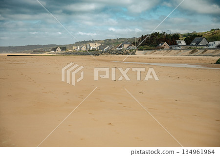 A wide view of Omaha Beach's peaceful shoreline in Normandy, France. Once a historic World War II landing site, the beach now offers a calm and reflective coastal landscape. A wide view of Omaha Beach's peaceful shoreline in Normandy, France. Once a historic World War II landing site, the beach now offers a calm and reflective coastal landscape. 134961964