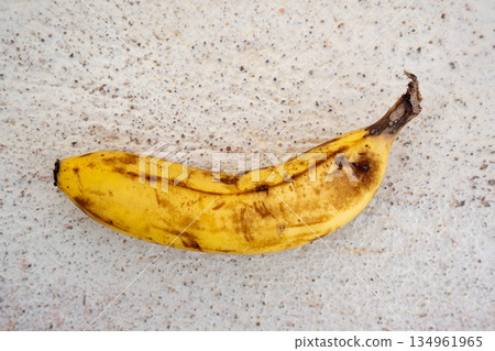 Overripe banana lying on speckled stone surface Overripe banana lying on speckled stone surface 134961965