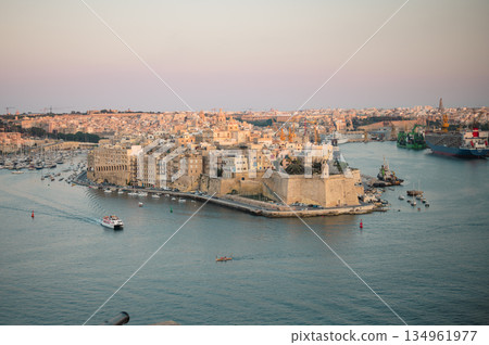 A stunning panoramic view of Birgu Port as seen from a Valletta vantage point, showcasing historic architecture, docked boats, and the scenic Maltese coastline. 134961977