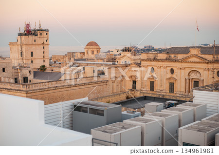 A stunning aerial view of Valletta's rooftops, showcasing the city's historic architecture, domes, and limestone buildings under the Mediterranean sky. A stunning aerial view of Valletta's rooftops, showcasing the city's historic architecture, domes, and limestone buildings under the Mediterranean sky. 134961981