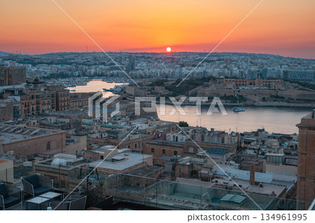 A stunning aerial view of Valletta's rooftops, showcasing the city's historic architecture, domes, and limestone buildings under the Mediterranean sky. A stunning aerial view of Valletta's rooftops, showcasing the city's historic architecture, domes, and limestone buildings under the Mediterranean sky. 134961995