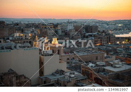 A stunning aerial view of Valletta's rooftops, showcasing the city's historic architecture, domes, and limestone buildings under the Mediterranean sky. A stunning aerial view of Valletta's rooftops, showcasing the city's historic architecture, domes, and limestone buildings under the Mediterranean sky. 134961997