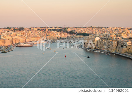 A stunning panoramic view of Birgu Port as seen from a Valletta vantage point, showcasing historic architecture, docked boats, and the scenic Maltese coastline. A stunning panoramic view of Birgu Port as seen from a Valletta vantage point, showcasing historic architecture, docked boats, and the scenic Maltese coastline. 134962001