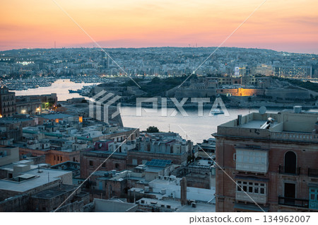 A stunning aerial view of Valletta's rooftops, showcasing the city's historic architecture, domes, and limestone buildings under the Mediterranean sky. A stunning aerial view of Valletta's rooftops, showcasing the city's historic architecture, domes, and limestone buildings under the Mediterranean sky. 134962007