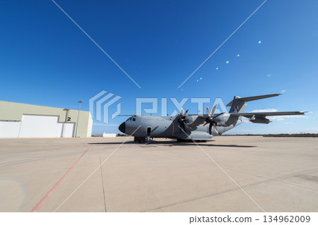 Military cargo aircraft near hangar on sunny day 134962009