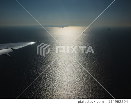 從飛往台灣的飛機舷窗望出去，景色蔚為壯觀：清晨的陽光照射在遠處的海面上，反射出一道光束。 134962294