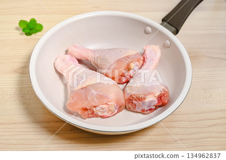Uncooked bone-in chicken in a frying pan Uncooked bone-in chicken in a frying pan 134962837