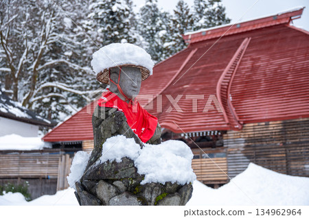 Jizo statue wearing a snow hat and a red apron 134962964