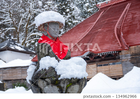 Jizo statue wearing a snow hat and a red apron | A Japanese religious scene at a temple in winter Jizo statue wearing a snow hat and a red apron | A Japanese religious scene at a temple in winter 134962966