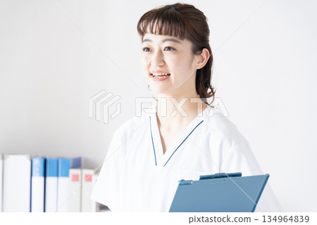 A woman in a white coat holding a file with a smile 134964839
