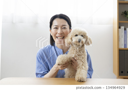 一位五十多歲的女子抱著一隻狗對著鏡頭說話 134964929