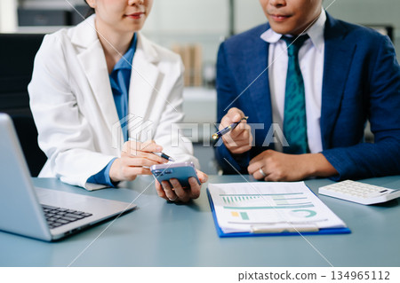 Professional businesspeople analyzing data, discussing strategy, and collaborating on financial reports in a modern corporate office setting. Professional businesspeople analyzing data, discussing strategy, and collaborating on financial reports in a modern corporate office setting. 134965112